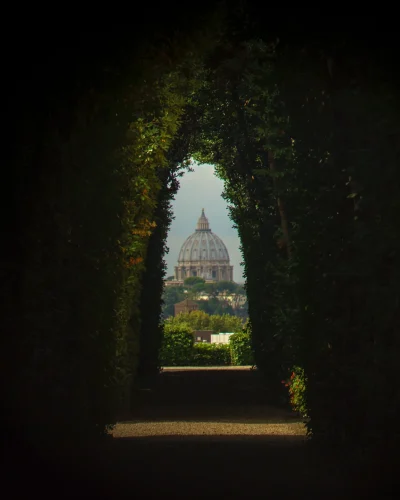 A unique view through the Aventine Keyhole in Rome, providing a framed perspective of St. Peter's Basilica in the distance. The image highlights the intriguing and lesser-known vantage point that offers a stunning view of the iconic dome.