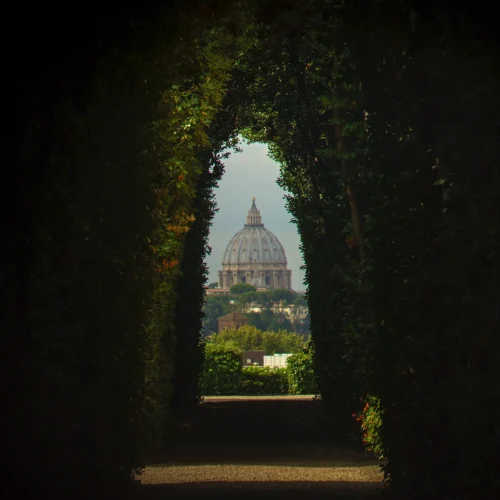 A unique view through the Aventine Keyhole in Rome, providing a framed perspective of St. Peter's Basilica in the distance. The image highlights the intriguing and lesser-known vantage point that offers a stunning view of the iconic dome.